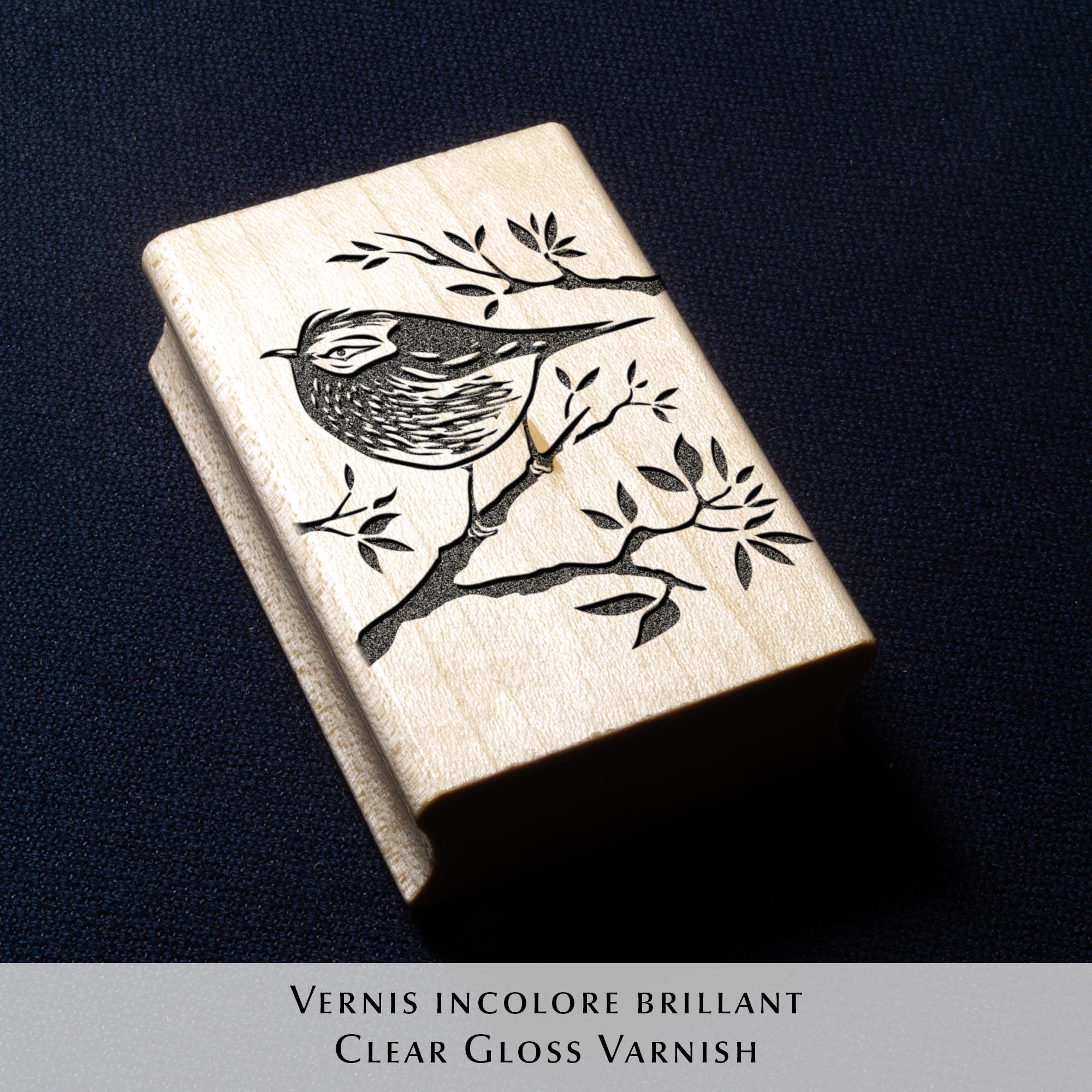Tampon ex-libris en bois et caoutchouc The Kinglet de Clément Scarpi. Marque-page et accessoire de bibliothèque personnalisé représentant une empreinte de gravure de roitelet (oiseau) sur une branche avec l'inscription Ex Libris, posé sur les pages ouvertes d'un livre.
