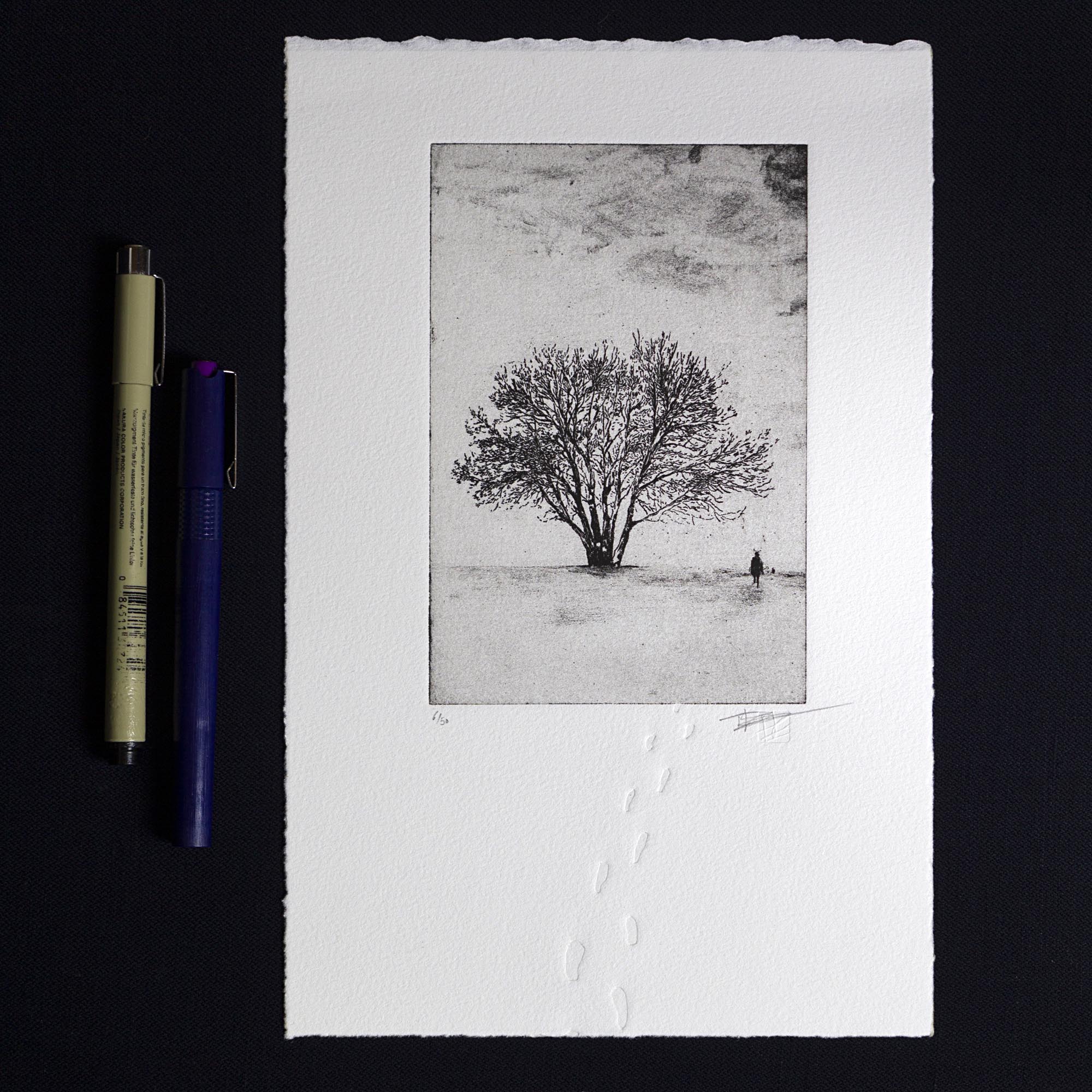 Gravure originale Footprints in the snow de Clément Scarpi. Estampe d'art en noir et blanc représentant un paysage d'hiver enneigé avec un cycliste au loin et des traces de pas en relief (gaufrage) sur papier d'art Velin Arches BFK Rives.