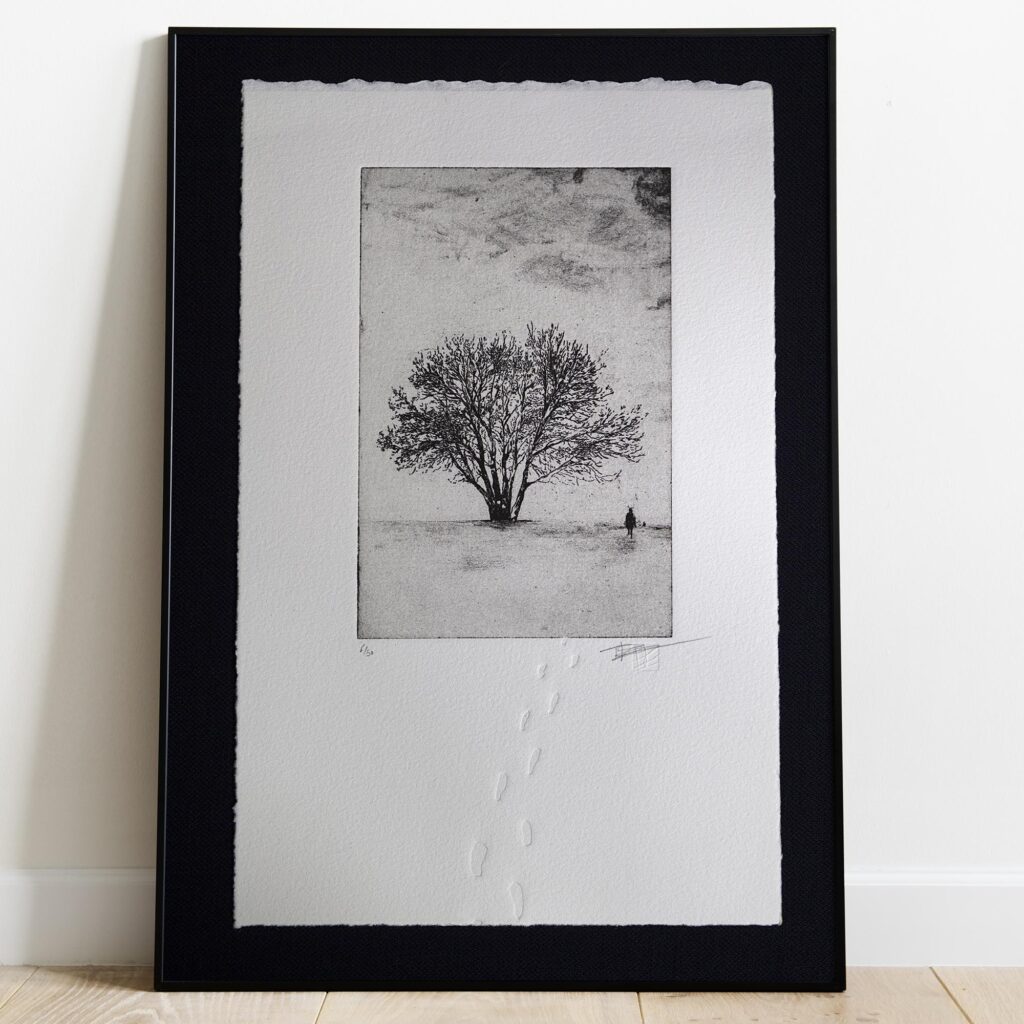 Gravure originale Footprints in the snow de Clément Scarpi. Estampe d'art en noir et blanc représentant un paysage d'hiver enneigé avec un cycliste au loin et des traces de pas en relief (gaufrage) sur papier d'art Velin Arches BFK Rives.