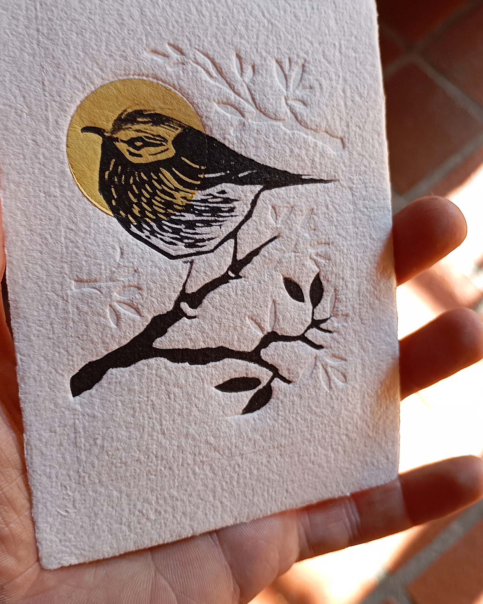 Gravure "Golden Crown Kinglet" sur papier d'art blanc épais et texturé à bords frangés, présentée dans un cadre noir texturé, posée sur un parquet en bois clair contre un mur blanc.