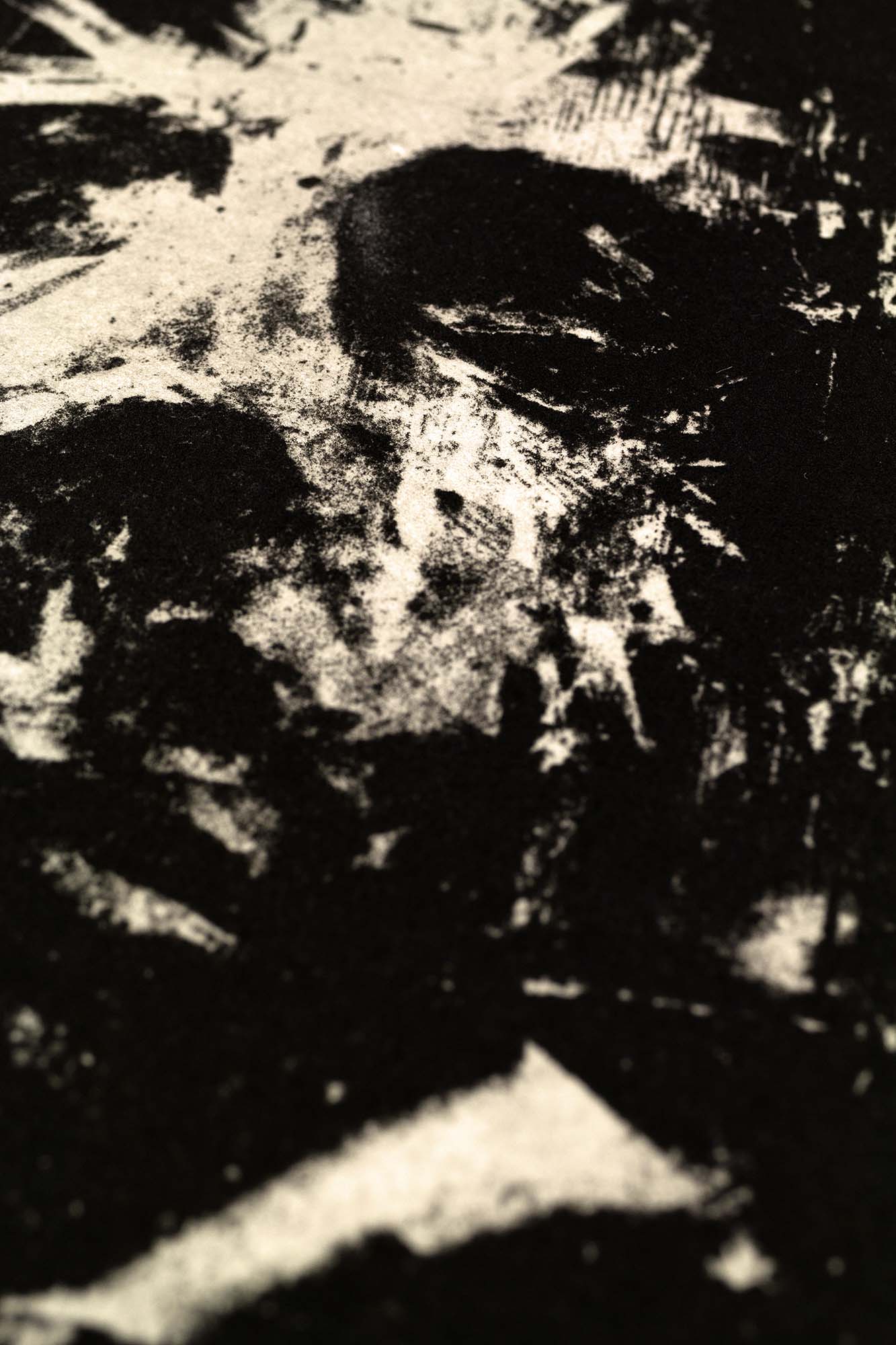 Gravure expressionniste en noir et blanc "Portrait" dans un grand cadre noir fin avec un passe-partout blanc, posée au sol sur un parquet clair contre un mur blanc.