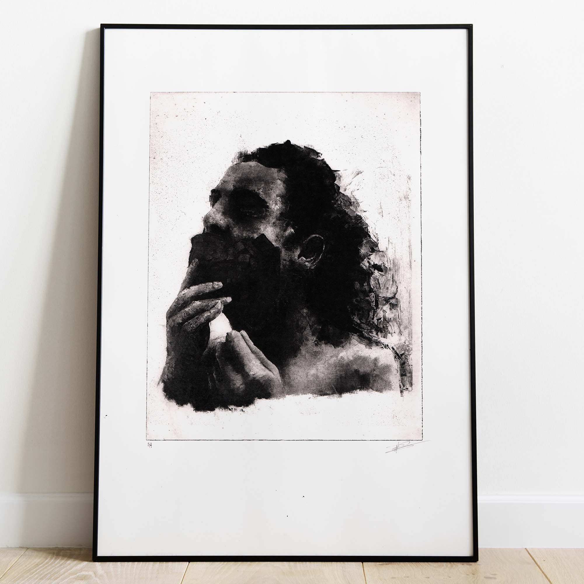 Mise en situation d'un grand cadre noir rectangulaire posé sur un sol en parquet de bois clair contre un mur blanc. À l'intérieur, un large passe-partout blanc met en valeur une estampe verticale à l'encre noire. L'illustration montre un visage masculin fragmenté et ténébreux, émergeant de touches d'encre texturées et de lignes gravées à l'esthétique brute et mélancolique. Sous la gravure, on distingue les inscriptions au crayon « EA » à gauche et la signature de l'artiste à droite.