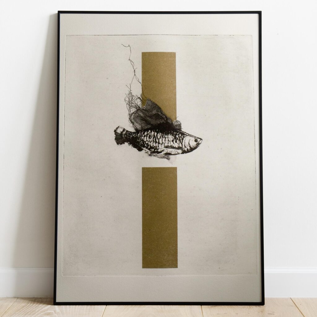 Gravure originale d'art contemporain The Fish de Clément Scarpi. Estampe d'art en noir et blanc représentant un poisson détaillé pris dans un filet, superposé sur deux rectangles dorés en arrière-plan (technique du chine-collé ou feuille d'or), présentée dans un cadre noir élégant.