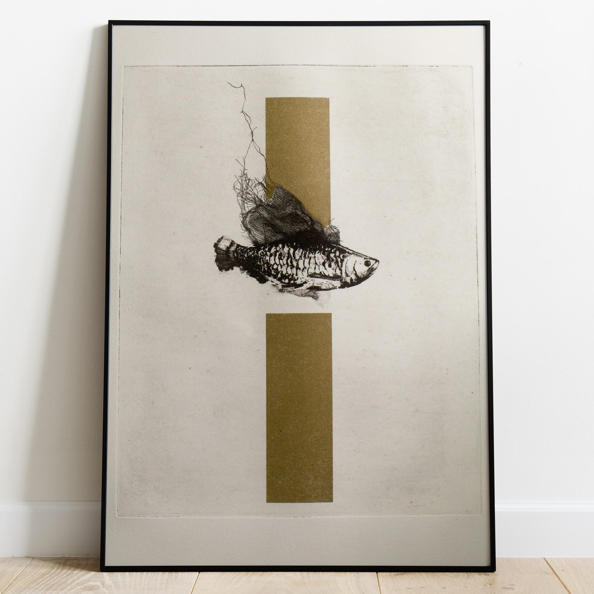 Gravure originale d'art contemporain The Fish de Clément Scarpi. Estampe d'art en noir et blanc représentant un poisson détaillé pris dans un filet, superposé sur deux rectangles dorés en arrière-plan (technique du chine-collé ou feuille d'or), présentée dans un cadre noir élégant.