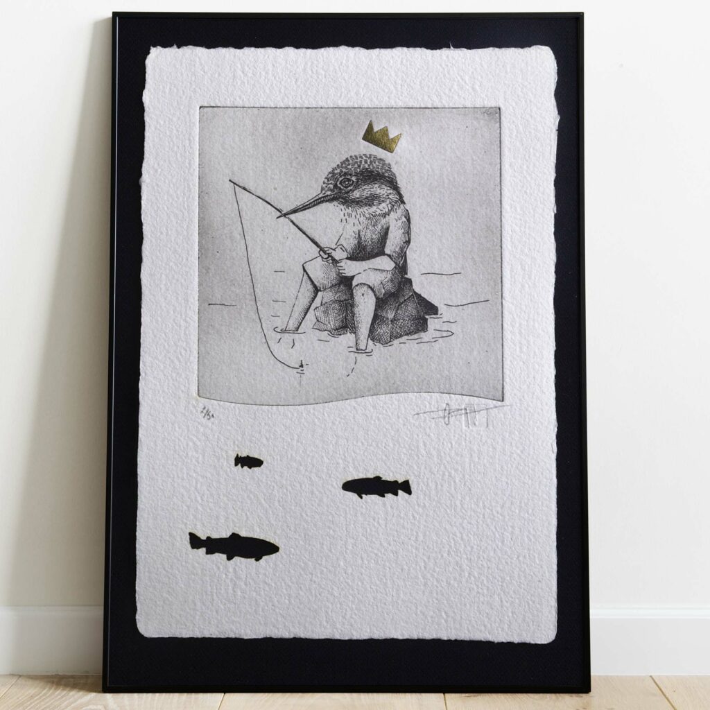 Gravure originale en noir et blanc intitulée "The King Fisher", représentant un martin-pêcheur, présentée dans un cadre en bois clair et exposé dans un intérieur lumineux au style épuré.